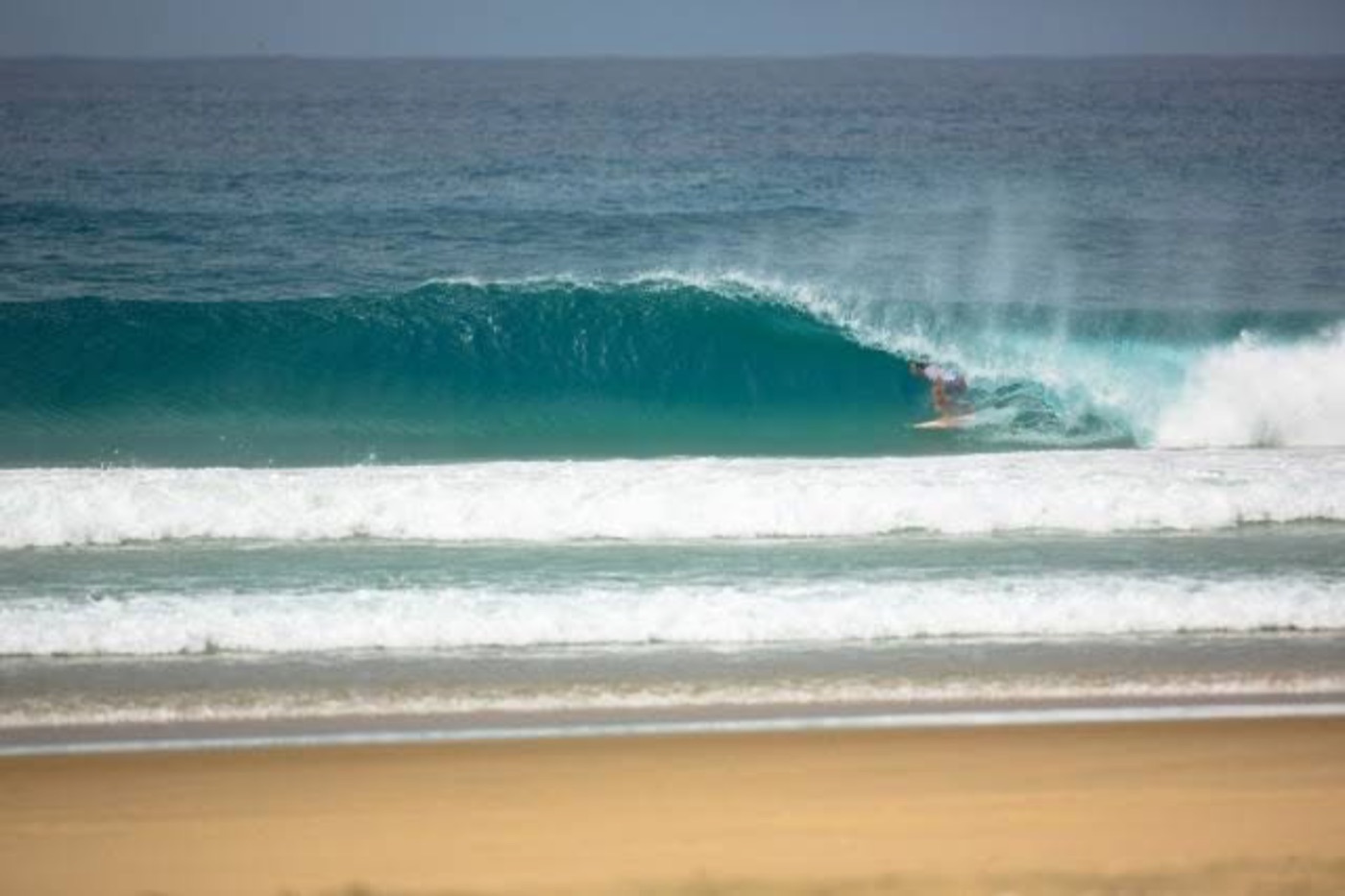 Perfect empty barrel peeling along the beach