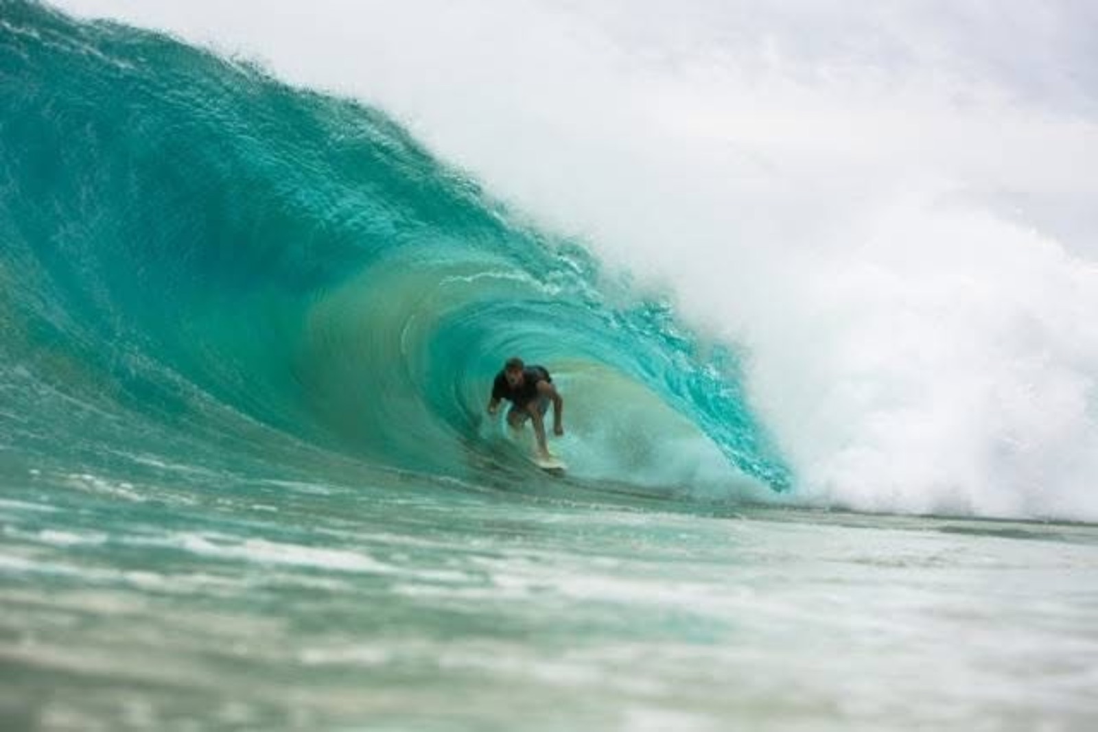 Surfer tucked into a turquoise barrel